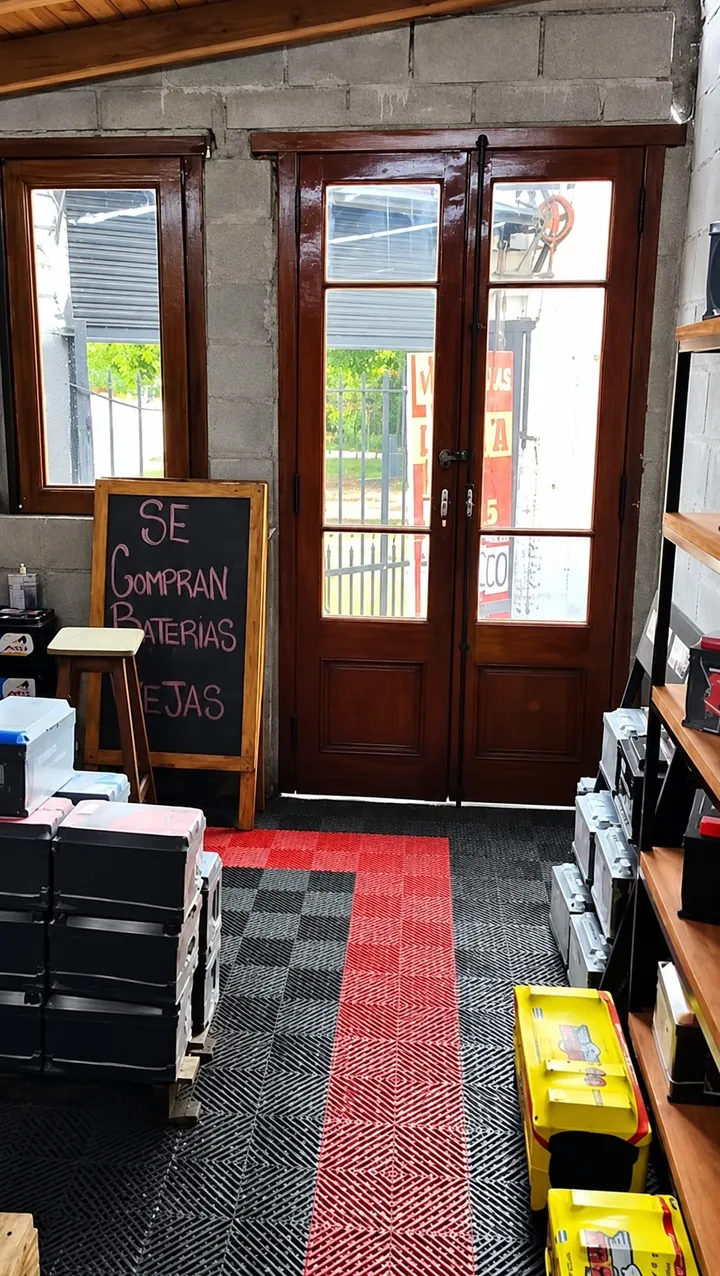 Entrada del local: puertas de madera, la pizarra «Se compran baterías» y el carril rojo en el piso
